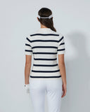 Person wearing a black and white striped polo shirt and white pants on a plain background