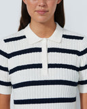 Woman wearing a white and navy striped shirt against a plain background