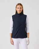 Woman wearing a navy blue vest over a white shirt on a light gray background