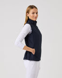 Woman wearing a navy vest over a white shirt on a light gray background