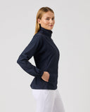 Woman wearing a navy blue turtleneck sweater and white pants on a light gray background