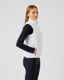Woman wearing a white puffer vest over a black long-sleeve shirt on a light gray background