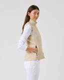 Woman wearing a beige vest over a white shirt on a light gray background