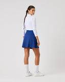 Person wearing a white long-sleeve top and blue skirt on a light gray background