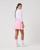 Person wearing a white long-sleeve top and pink skirt on a light gray background