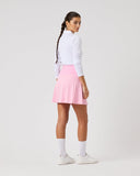 Person wearing a white long-sleeve top and pink skirt on a light gray background