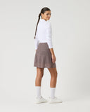 Woman wearing a white shirt, brown skirt, and white shoes on a light gray background