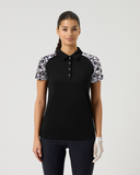 Woman wearing a black polo shirt with floral sleeves on a white background