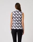 Woman wearing a sleeveless patterned top and black pants on a plain background