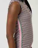Person wearing a sleeveless checkered dress with pink trim on a plain background