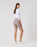 Woman wearing plaid shorts and a white shirt on a plain background