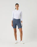 Woman wearing a white polo shirt and blue patterned shorts on a white background