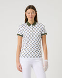 Woman wearing a patterned polo shirt and white pants on a plain background