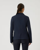 Person wearing a navy blue blazer and pants on a light gray background