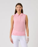 Woman wearing a pink sleeveless polo shirt and white pants on a light gray background