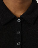 Close-up of a black polo shirt with buttons on a neutral background