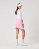 Woman wearing a white shirt, pink skirt, and visor on a white background