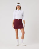 Woman wearing a white shirt, maroon skirt, and white shoes on a white background
