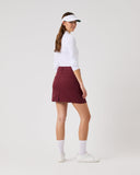Woman wearing a white shirt, maroon skirt, and visor on a white background
