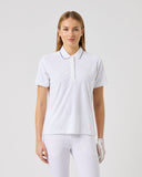 Woman wearing a white polo shirt and pants on a light gray background