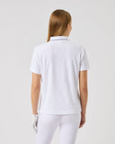 Woman wearing a white polo shirt and pants on a light gray background