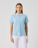 Woman wearing a light blue polo shirt and white pants on a gray background