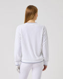 Woman wearing a white long-sleeve top and pants on a light gray background