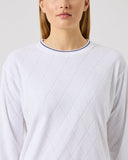 Person wearing a white quilted sweater against a plain background