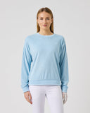Woman wearing a light blue sweater and white pants on a gray background
