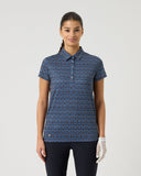 Woman wearing a navy blue patterned polo shirt on a light gray background