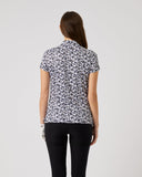 Woman wearing a patterned shirt and black pants on a plain background