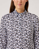 Person wearing a leopard print shirt against a plain background