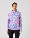 Woman wearing a pink and blue patterned long-sleeve shirt on a gray background