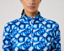 Woman wearing a blue and white patterned jacket on a plain background