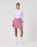 Woman wearing a white shirt, pink skirt, and white shoes on a white background