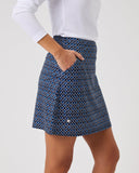 Person wearing a blue patterned skirt on a plain background