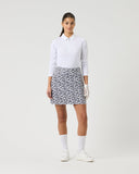 Woman wearing a white polo shirt and patterned skirt on a white background