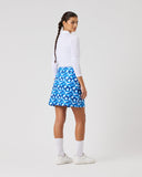 Person wearing a white top and blue floral skirt on a plain background