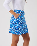 Person wearing a blue patterned skirt and white top on a light gray background