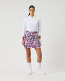 Woman wearing a white shirt and patterned skirt on a plain background