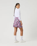 Person wearing a white long-sleeve top and pink patterned skirt on a white background