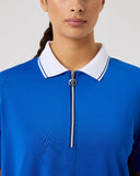 Woman wearing a blue polo shirt with a white collar on a gray background