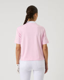 Person wearing a pink polo shirt and white pants on a light gray background
