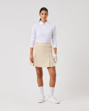 Person wearing a white shirt, beige skirt, and white shoes on a plain background