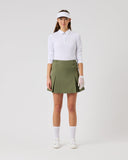 Woman wearing a white shirt, green skirt, and white visor on a light gray background