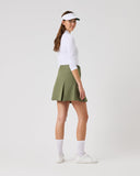 Woman wearing a white shirt, green skirt, and visor on a white background