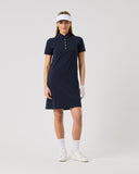 Woman wearing a navy blue dress with white accents on a light gray background