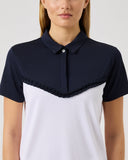 Woman wearing a two-tone shirt with a navy collar and white body on a plain background