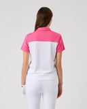 Woman wearing a pink and white polo shirt with white pants on a light gray background