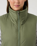 Person wearing a green puffer vest against a plain background